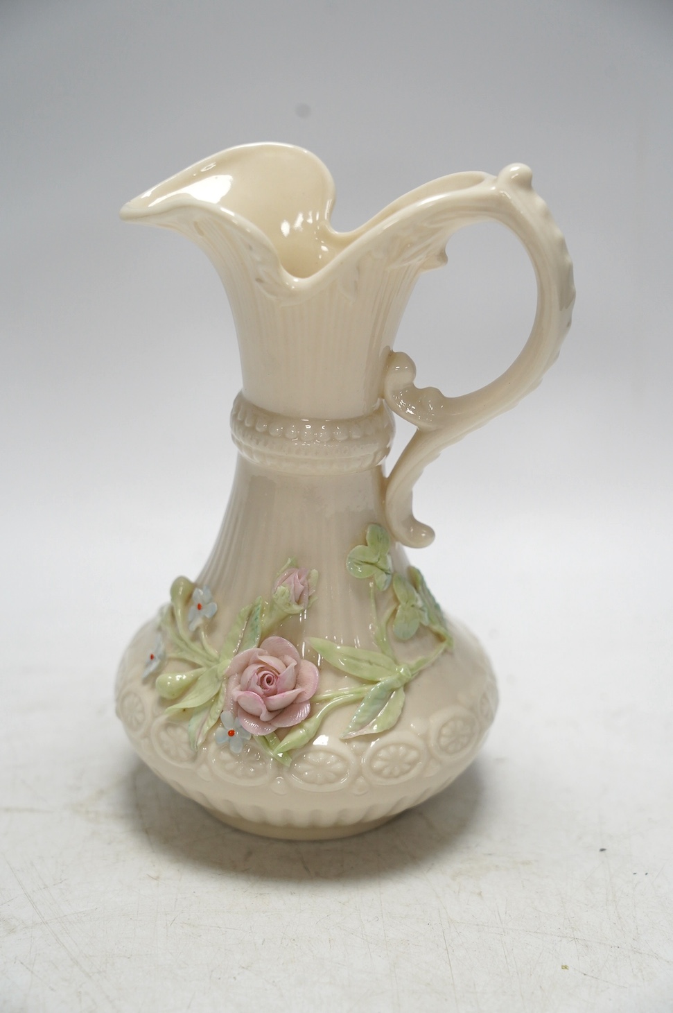 Three 20th century Belleek items with applied floral decorations; a jug, 15cm high, and two basket work dishes, largest 20cm wide. Condition - good